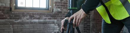 Areamätare i varselväst med laserskanner för areamätning och planritning i lokal