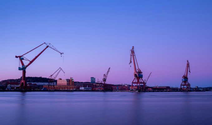 Kranarna vid Göteborgs hamn i skymning. Foto: Nikola Johnny Mirkovic / Unsplash